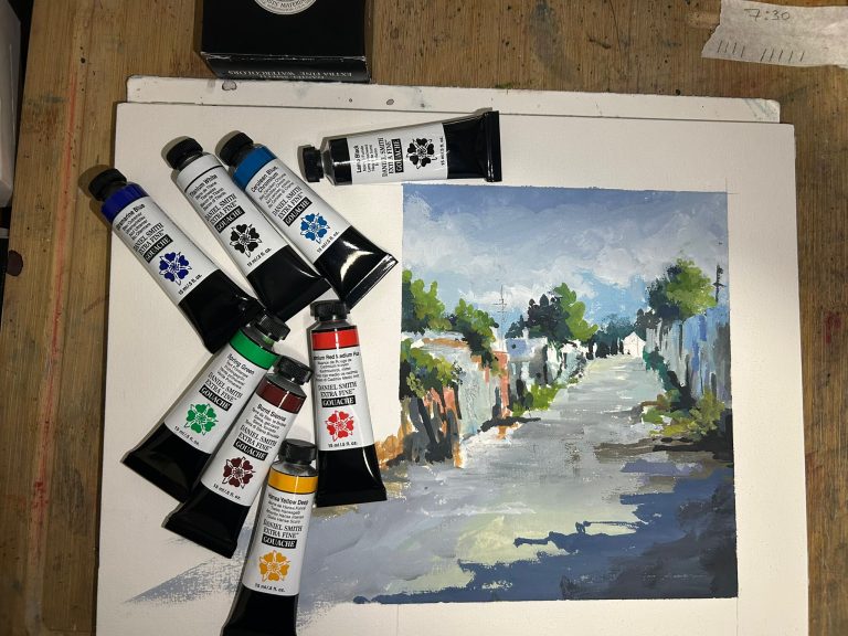 Tubos de gouache junto a una pintura urbana sobre papel