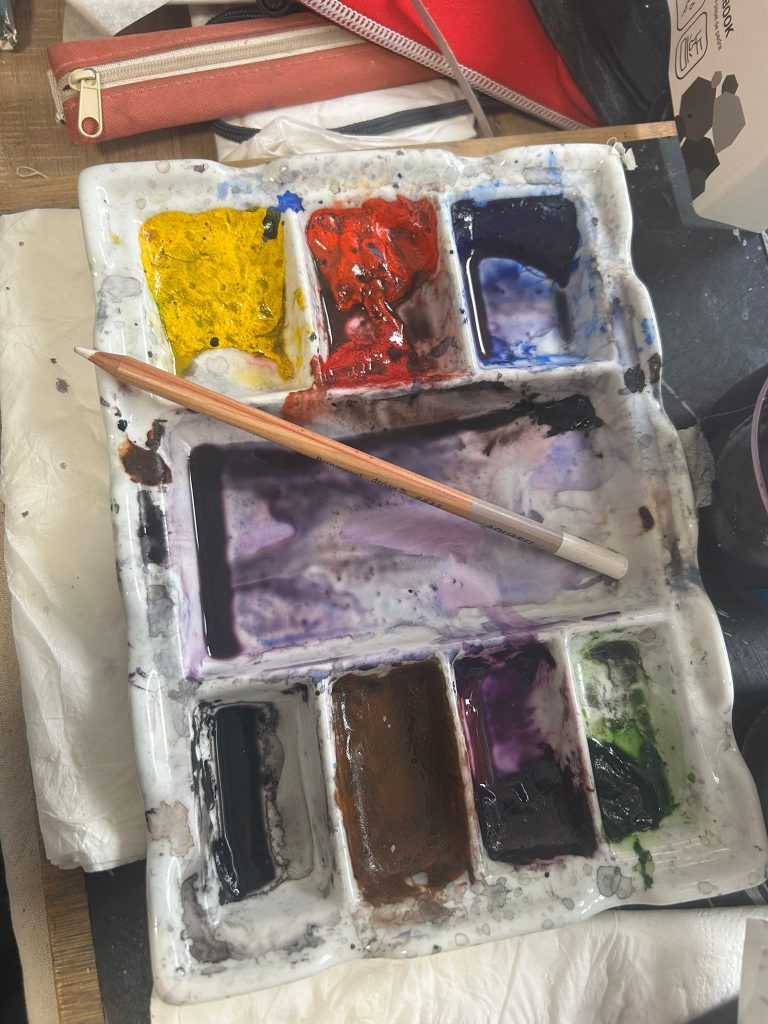 Paleta de acuarela con mezclas de color y un pincel