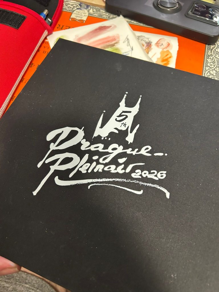 Cubierta negra de un cuaderno con la inscripción Prague Pleinair 2026