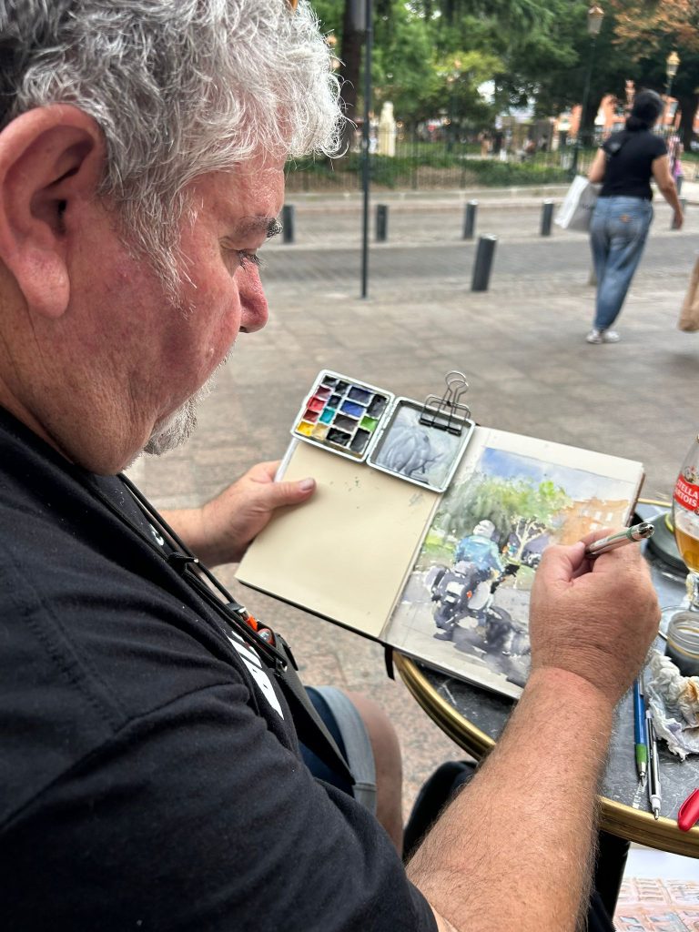 Proceso de dibujo y acuarela en un cuaderno sobre una mesa de terraza
